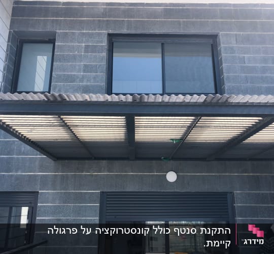 גג מתכת מעל חלון גדול עם תריסים